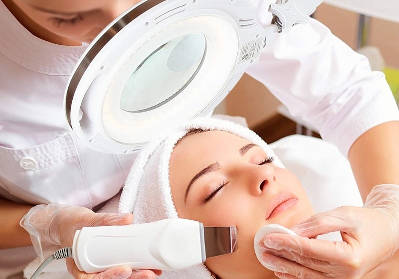 Kỹ thuật viên spa dùng đèn soi da cho khách hàng